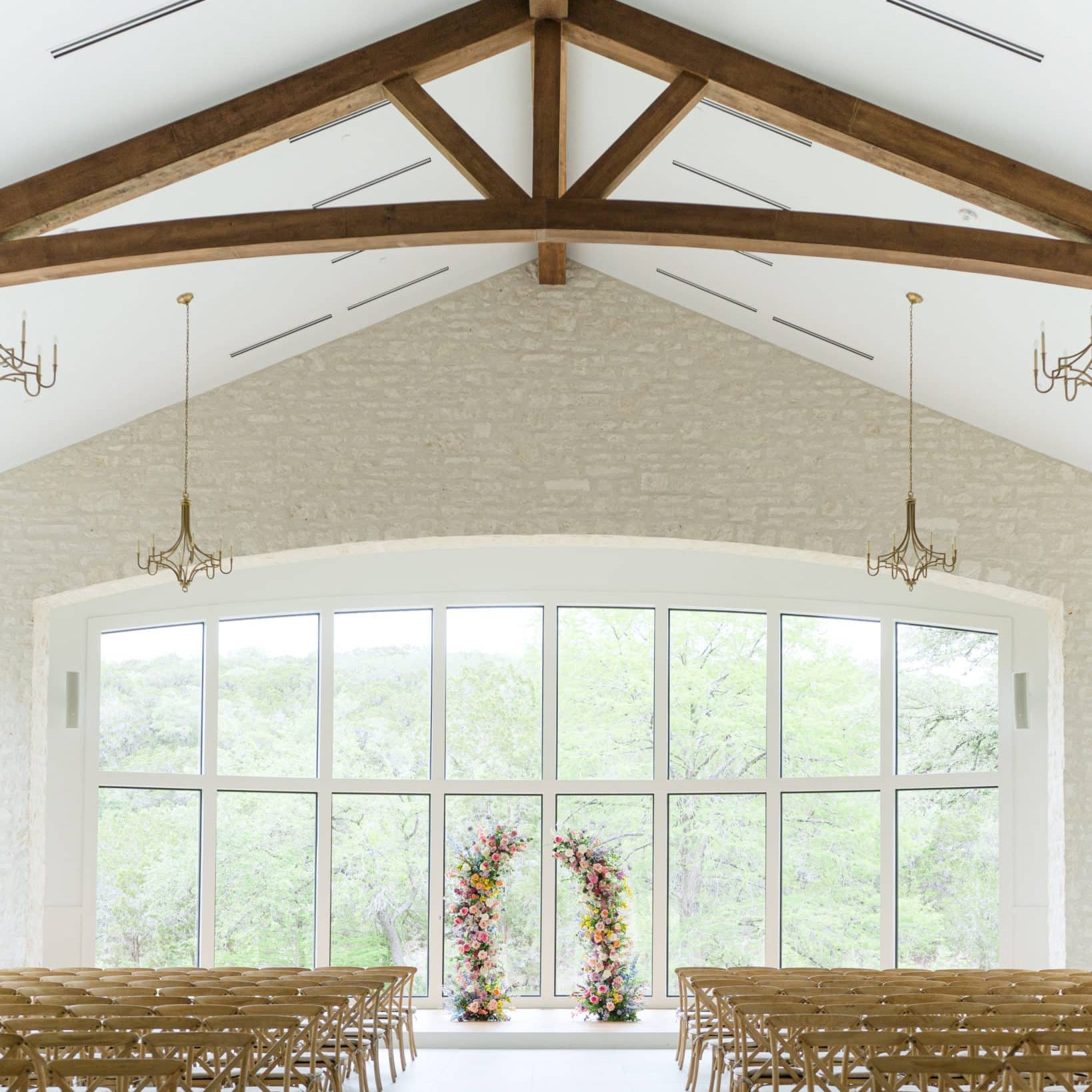 Wedding chapel with floral pillars, chandeliers, and wood trusses