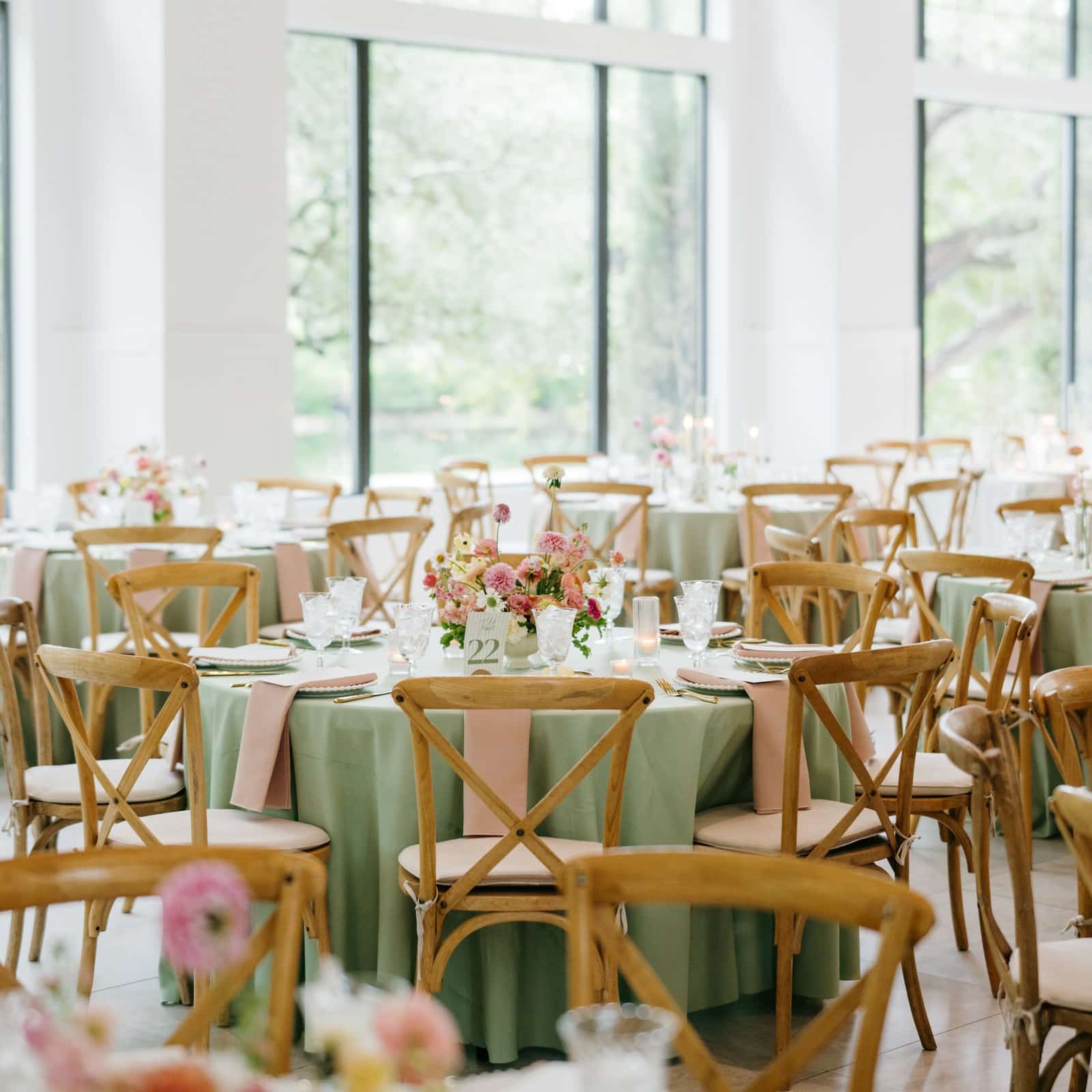 Round reception tables with sage green linens, blush napkins and pink floral centerpieces in The Preserve at Canyon Lake ballroom