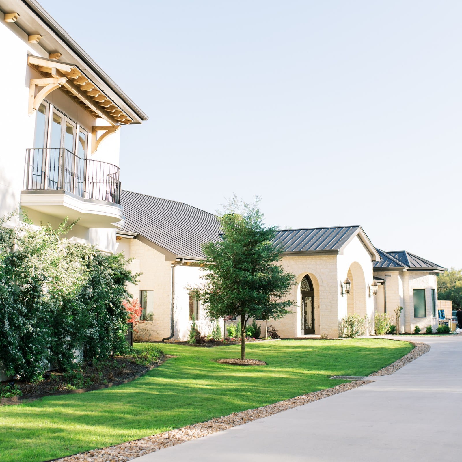 Exterior of The Preserve at Canyon Lake wedding venue with balcony, green lawn and curved drive